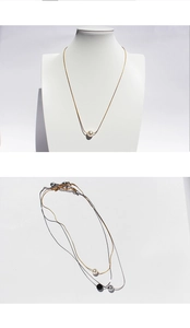 Detail showing minimalist gold and silver chains with white black and grey pearl pendants