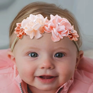 Close-up of pink satin flower headband with pearls and rhinestones on a baby