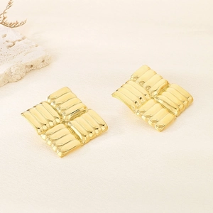 Golden square earrings with woven texture on a minimalist light fabric background
