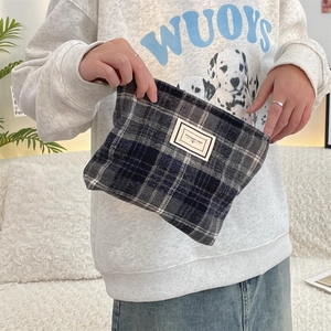 Detail of grey checkered wool makeup bag with Pleasant Time label held in hand