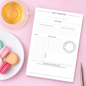 Flat lay of an English daily devotional planner with a pen and macarons on pink background