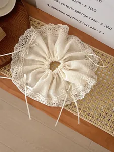 Close-up of beige lace scrunchie with delicate mesh bow and bead detail on wooden desk