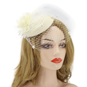 Detail of beige fascinator hat with delicate white mesh veil and pearl embellishments