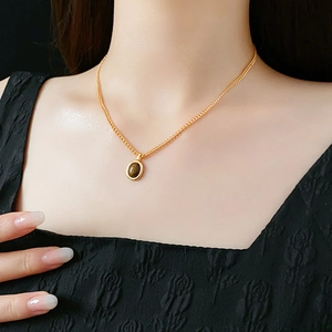 Gros plan d'un collier doré avec pendentif ovale marron sur une robe noire chic