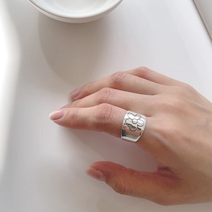 Detailed view of an S925 silver wide ring featuring vintage flower patterns worn on a finger