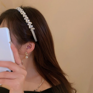 Close-up of sparkling rhinestone headband and pearl earring on a female model