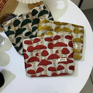 Detailed view of mushroom jacquard fabric cosmetic bags in red, yellow, and green colors