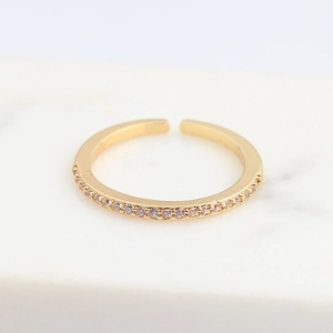 Close-up of golden open ring with micro-pave pink zircons on white marble surface