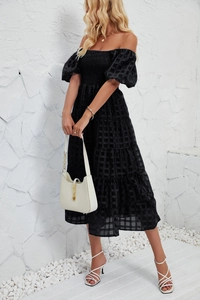Detail of black tiered dress featuring smocked bodice and textured checkered fabric