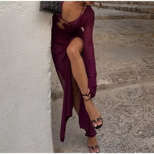 Detalle de un vestido largo de ganchillo morado oscuro con aberturas laterales y recortes