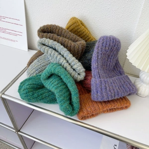 Detailed texture of thick chunky knit wool beanies in various warm winter colors