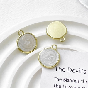 Detailed macro view of gold enamel round disk charms for DIY jewelry crafting