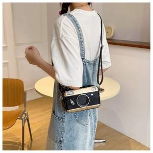 Detail of a mini camera-shaped crossbody bag in black and gold PU leather with a strap