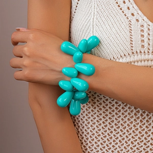 Detail of turquoise teardrop beaded bracelet on model with white crochet top