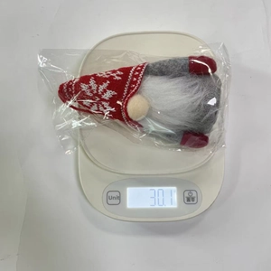 Macro detail of glowing Christmas gnome with red snowflake hat on a digital scale