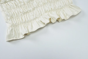 Detail of cream white pleated chiffon fabric and ruffle hem with smooth satin-like texture