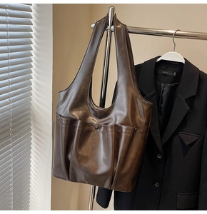 Detail of deep brown PU leather tote bag with functional pockets and pleated texture