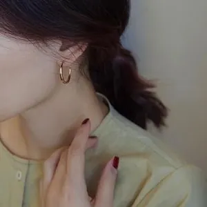 Detailed view of polished gold hoop earrings on a model with minimalist design