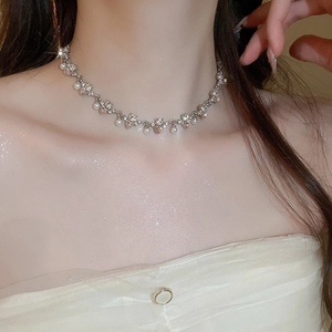 Detail of elegant heart pearl necklace with rhinestones worn on neck by a model