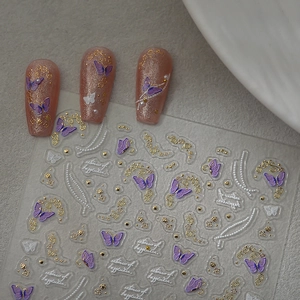 Detail of 3D embossed nail stickers featuring butterflies, flowers, and white pearls