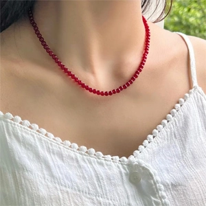 Detail of elegant red agate bead necklace worn on neck with natural green backdrop