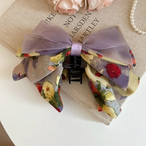 Detail of a large bow hair claw clip with lilac organza and floral pattern fabric textures