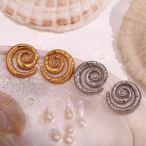 Macro shot of 18K gold and silver spiral earrings with zircon on shells and water drops