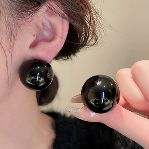 Detail view of large minimalist black sphere stud earring with glossy mirror finish