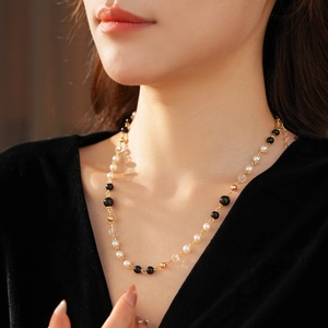 Détail d'un collier de perles vintage avec perles noires sur une robe en velours noir