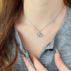 Détail d'un collier pendentif cheval en argent avec zircon porté sur un pull gris chic