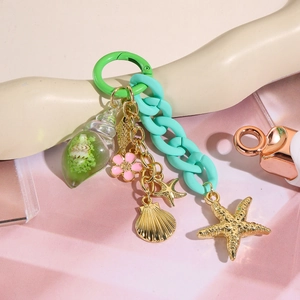 Gros plan d'un porte-clés perlé vert avec breloques étoile de mer et coquillage