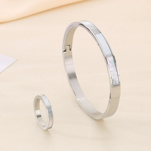 Detailed macro view of silver stainless steel bangle and ring set with white shell inlay