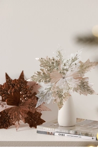 Elegant gold and bronze poinsettia artificial flowers in a white ceramic vase on books