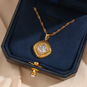 Detail showing the golden square pendant with a radiant spiral texture and clear zircon