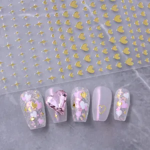Close-up of gold heart and star nail stickers with pink heart gems on marble background