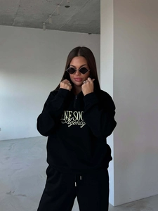 Detail of black half-zip sweatshirt with golden LINE SOC Agency embroidery on the chest