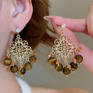 Detail of vintage gold-plated drop earrings with tiger eye beads and crystal studs