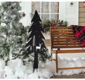 Black metal Christmas tree yard sign with reindeer cutout in a snowy garden porch