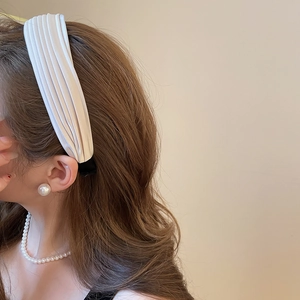 Détail du serre-tête plissé crème associé à un ensemble de bijoux en perles élégant