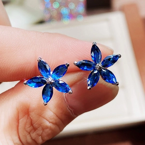 Macro shot of silver flower earrings with five blue marquise-cut zircon petals