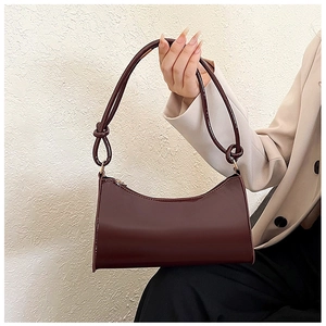 Detail of burgundy baguette bag with smooth finish and knot shoulder strap detail