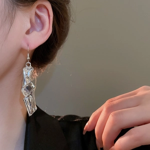 Close-up of silver irregular twisted earrings with liquid metal texture on a model