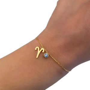 Gold stainless steel Aries zodiac bracelet with blue birthstone charm on model wrist