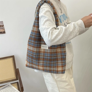 Detail of blue and brown plaid wool tote bag showing texture and woven shoulder strap