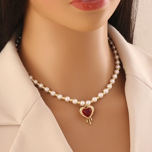 Fashion pearl beaded gold necklace with a red heart pendant worn by a model
