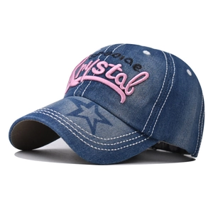 Detail of blue denim baseball cap featuring pink Crystal 3D embroidery and white stitching