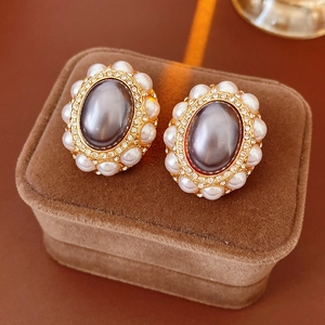 Detail of vintage gold earrings with grey stones and pearls on a brown velvet box