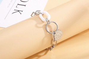 Gros plan sur un bracelet à maillons géométriques avec pendentif rond et maillons blancs