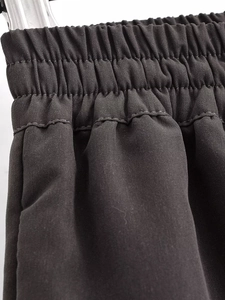 Detailed macro view of the elastic pleated waist and twill fabric on black casual trousers