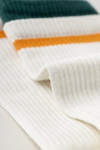 Close-up of white ribbed cotton yoga socks with green and yellow horizontal stripes